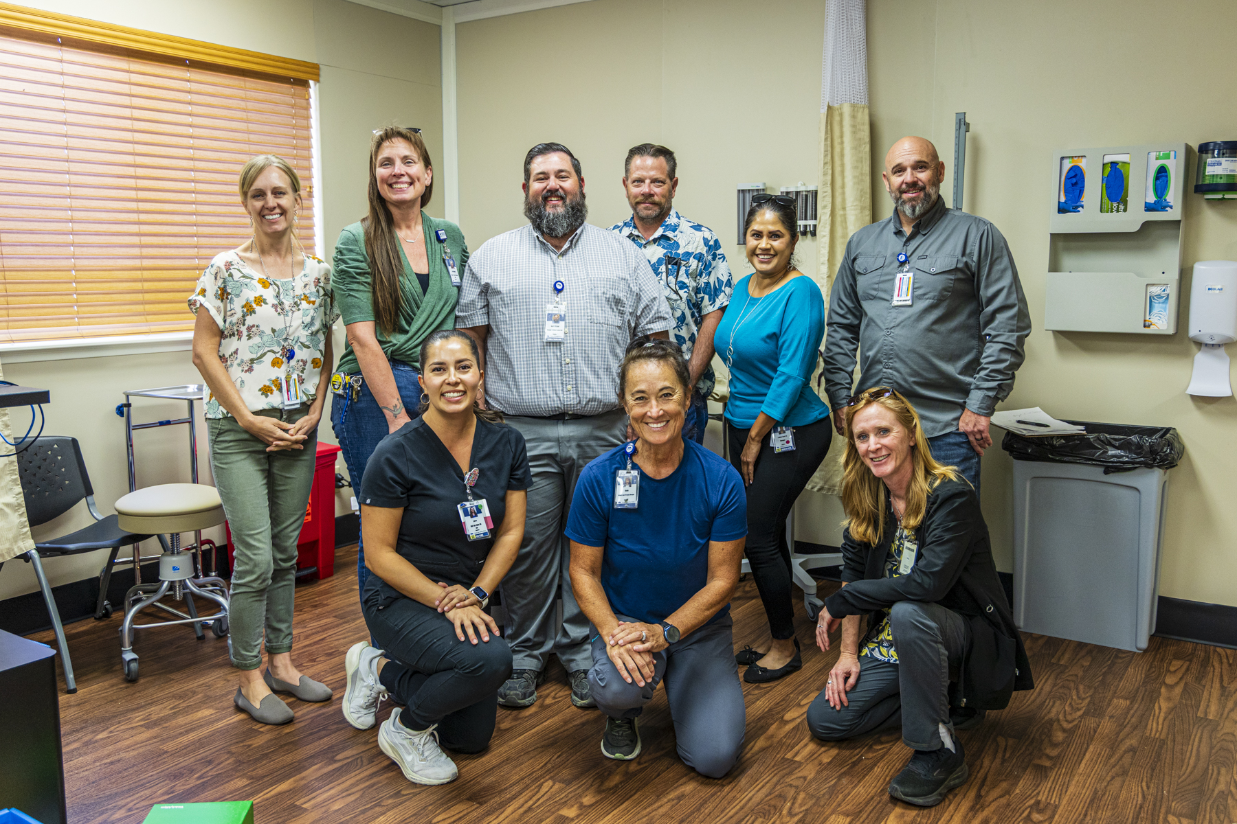 Nine NIHD team members who helped bring the Panther Clinic to life pose together in two rows.