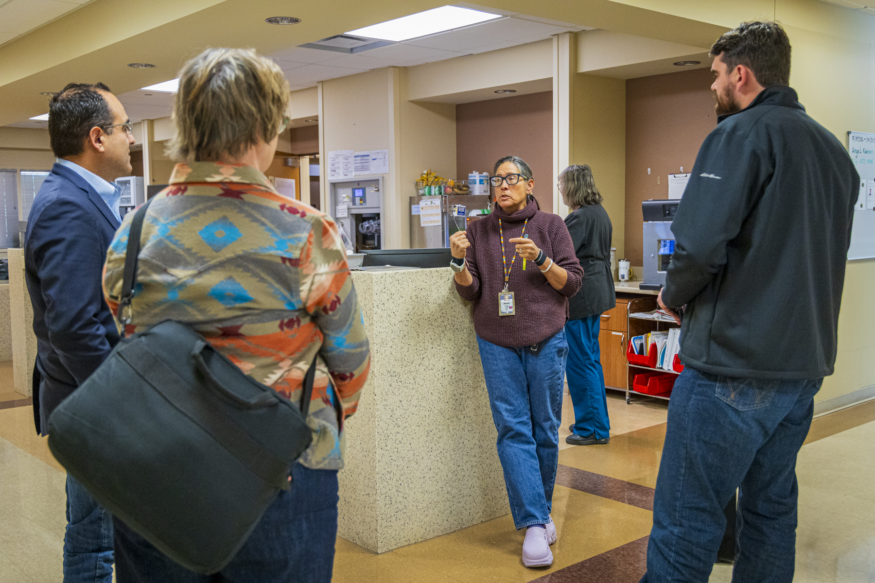 A female physician stands in a circle of three, talking candidly about the challenges facing frontier healthcare facilities.