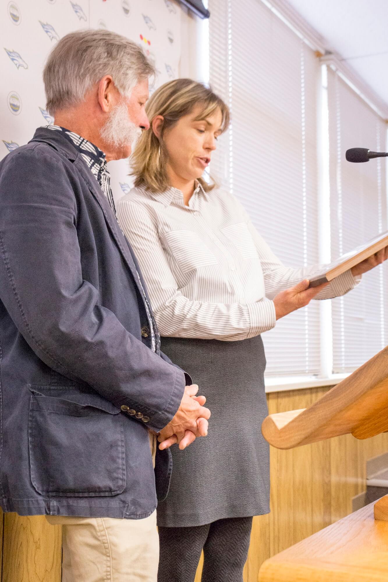 Bishop Mayor Karen Schwartz reads the inscription on the City of Bishop tile presented to Pete Watercott as he looks on. 